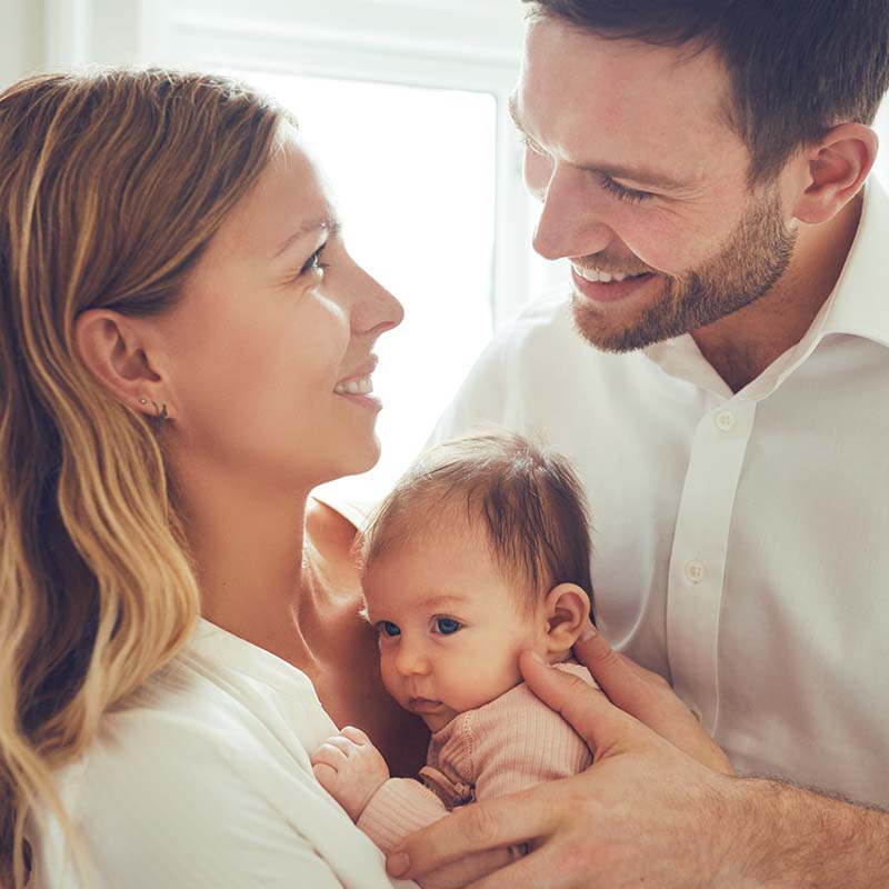 Portrait Photo of Family of Mother and Father Holding Their New Born after visiting Petite Crew